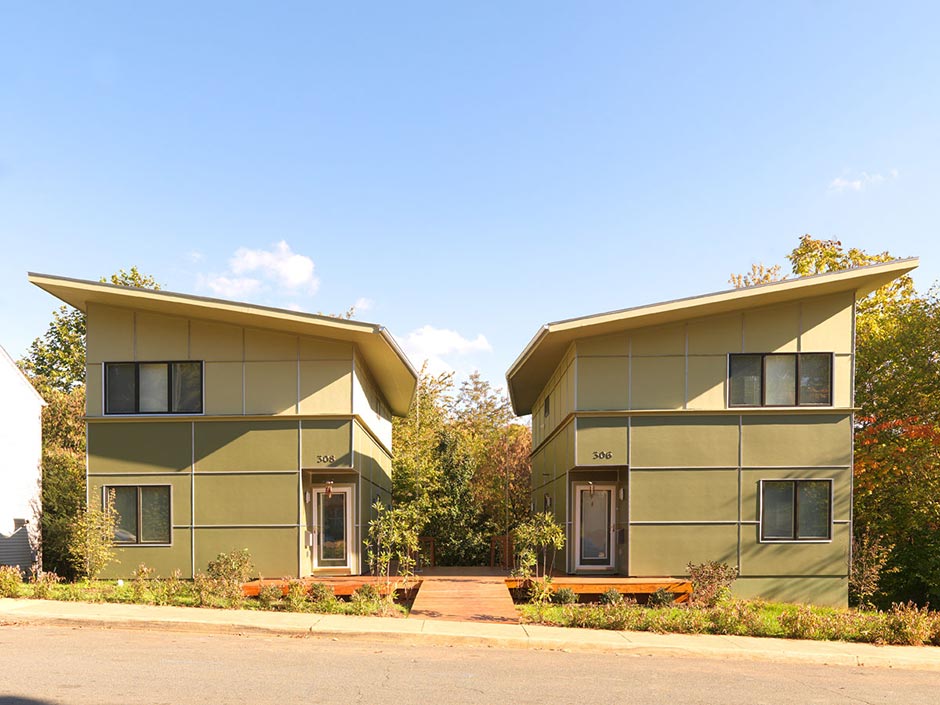 Two Hardi-Panel Clad Habitat for Humanity Houses with Roofs Slanting toward Common Courtyard. Rain Chains Collect Stormwater.