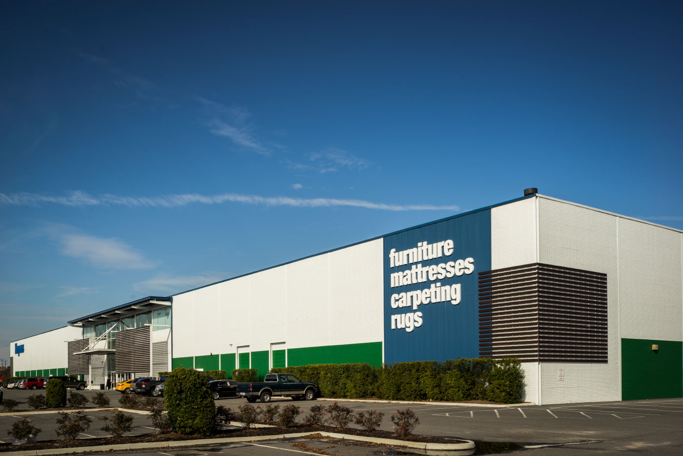 Long View of the Renovation of the Haynes Virginia Beach Showroom by Green and Modern Virginia-based HEDS Architects has Signage at the Corners on Blue Panel with White Lettering.