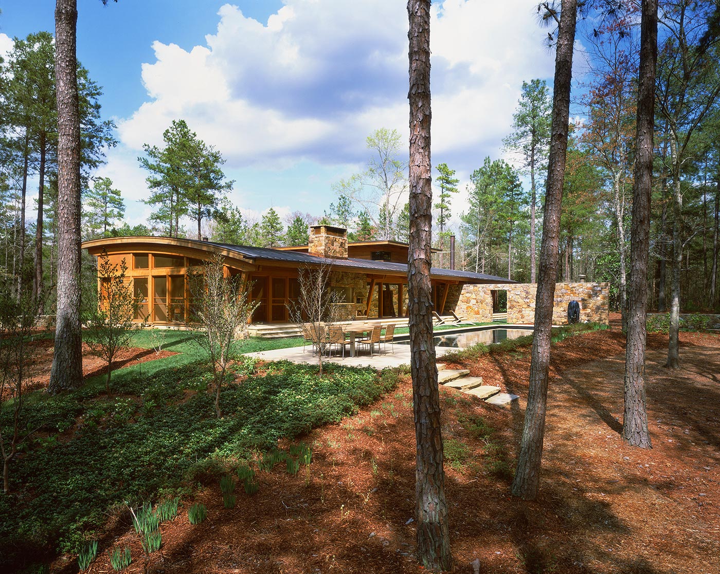 Standing Seam Curved Roof and Stone Walls Overlooking Pool Designed by Best Virginia Architects.